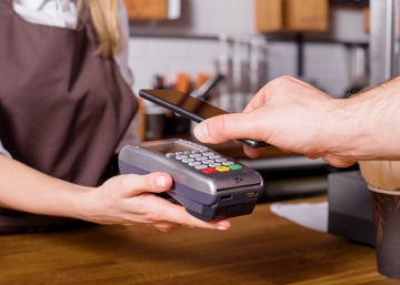 An individual in Hong Kong is operating both a cell phone and a pos machine.