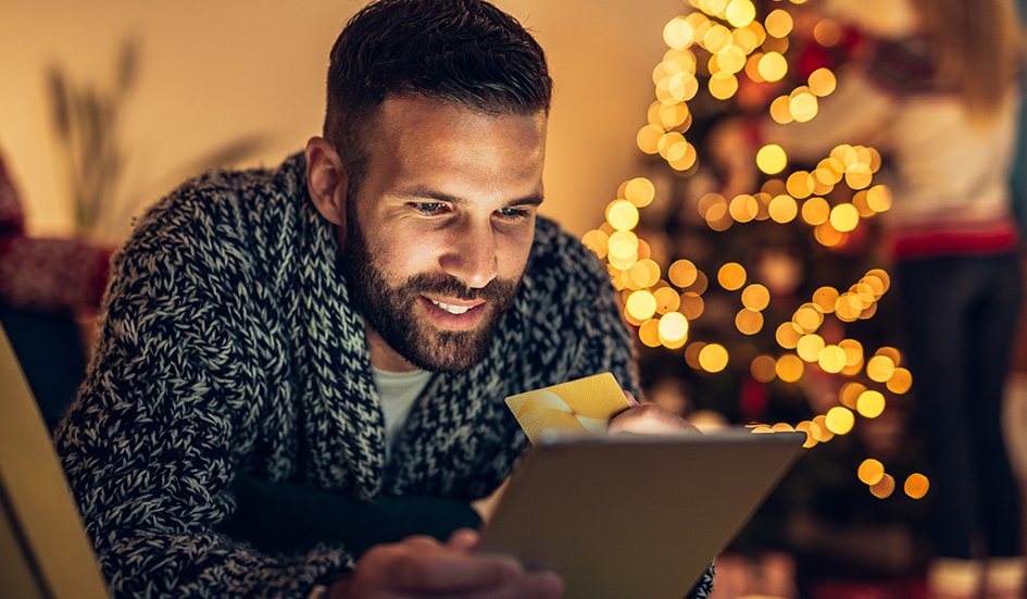 A man in Hong Kong looking at a tablet in front of a Christmas tree.