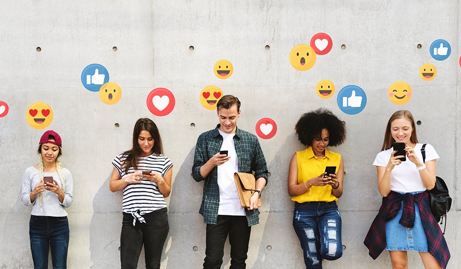 A group of people utilizing digital marketing techniques to capture award winning emojis on their phones in front of a wall.